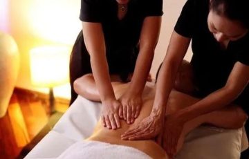 2 massage therapist performing four hand massage on a man's upper back in angle spa center g9 Islamabad