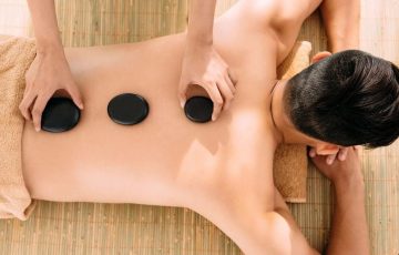 Massage therapist performing hot stone massage with 4 stones on a client's back in best spa center g9 Islamabad